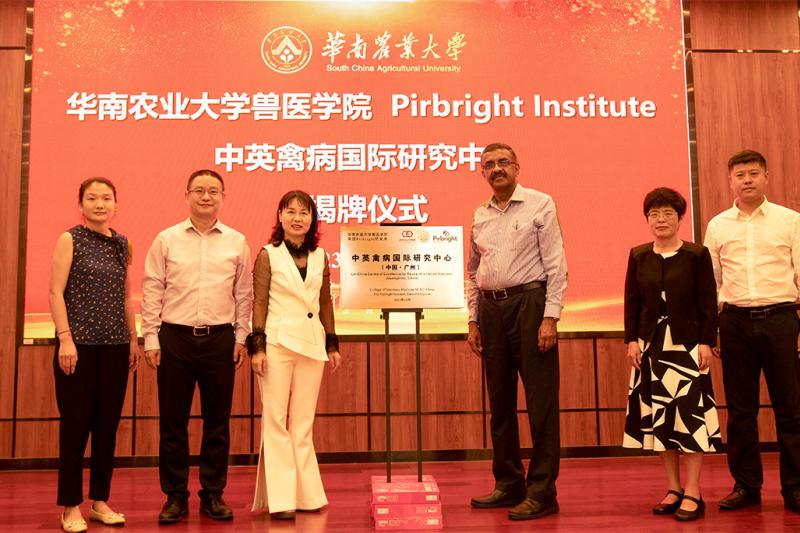 Six people stood around a plaque in front of a screen with a red backgroun containing text that reads Pirbright Institute and Chinese text. Pirbright's Venu Nair and Yongxiu Yao stood in the middle to the right of the plaque.
