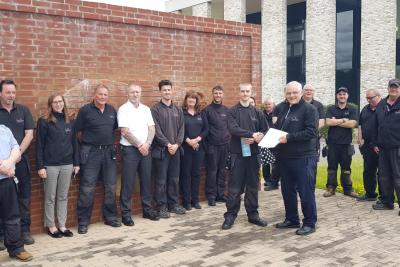 Members of the Estates and Engineering teams stood in front of brick Bull with presentation of certificate to one member