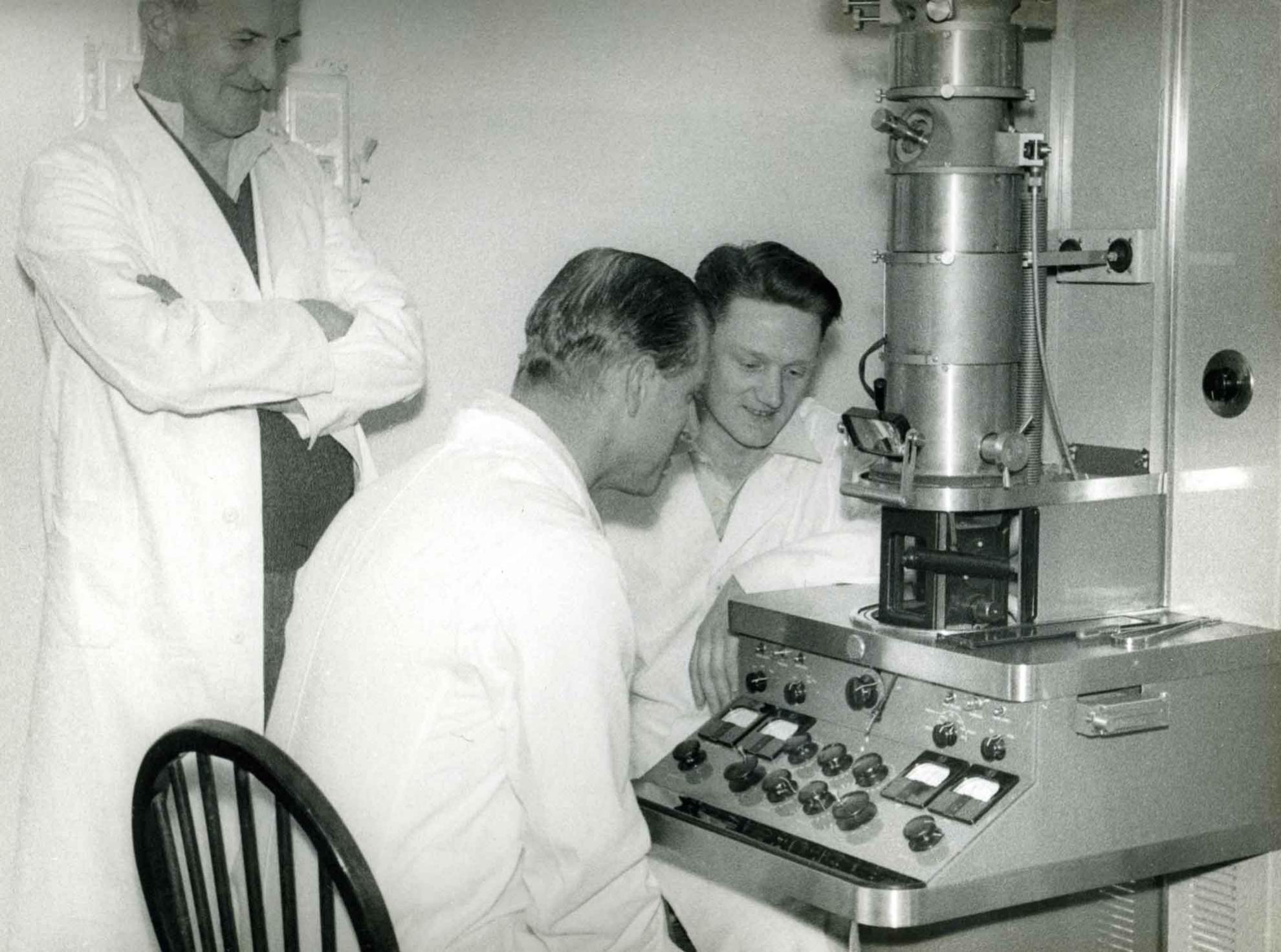 Prince Philip manning the electron microscope during his visit in 1956 with a young Fred Brown on the left. Prince Philip sits at early transmission electron microscope at Pirbright in 1956