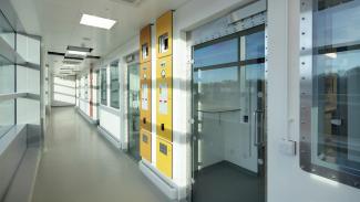 Sunlit laboratory corridor showing array of glass doors and bright yellow information panel
